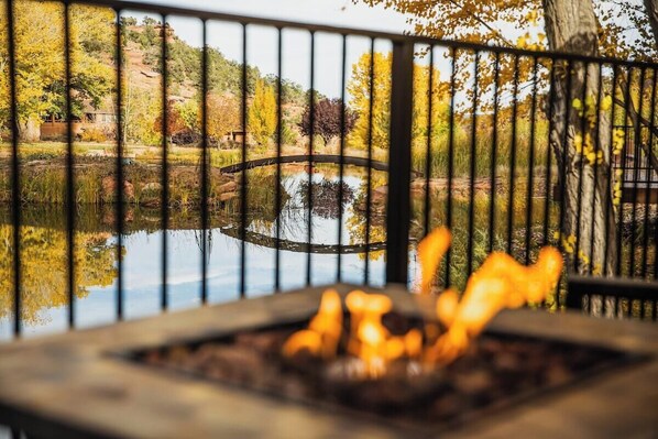 A fire pit with a view of a pond and trees.