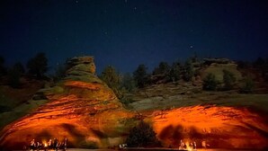 Escena nocturna con un paisaje rocoso iluminado por una luz cálida.