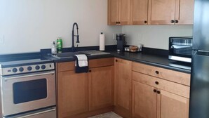 Una cocina con armarios de madera, estufa de acero inoxidable, refrigerador y cafetera.