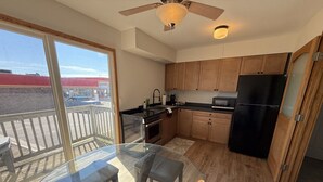 Una cocina moderna con armarios de madera, un refrigerador negro y una mesa de comedor de vidrio.