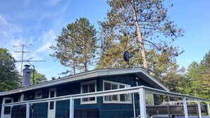 A house with a deck, large windows, and a satellite dish. - Luxury Winter Retreat/Direct Snowmobile Access (Spurr Township)