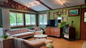 A cozy living room with a sofa, a small round table, and a television set. - Luxury Winter Retreat/Direct Snowmobile Access (Spurr Township)