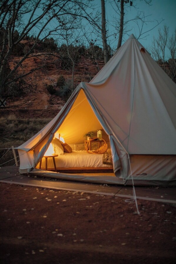 Una tienda en forma de cúpula con una cama en su interior, rodeada de un paisaje natural.