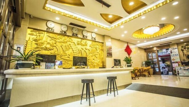 Un espace d’accueil d’hôtel comprenant un comptoir, des sièges et un mur décoratif.