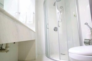 Un baño moderno con ducha de vidrio, inodoro blanco y lavamanos blanco.