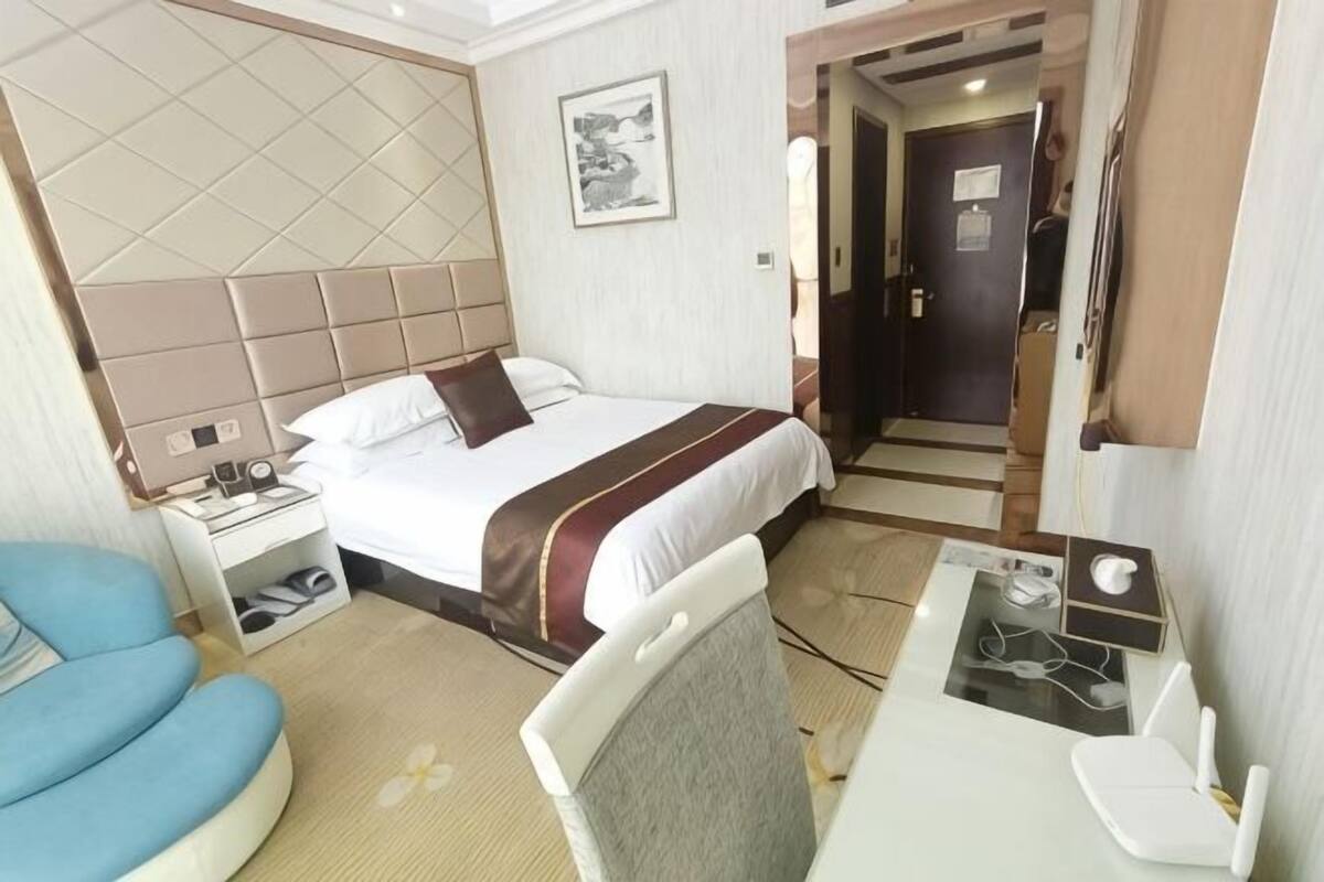 Une chambre d’hôtel comprenant un lit, une table de chevet, une chaise, un bureau et une porte donnant sur une autre pièce.