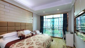 Une chambre d’hôtel avec un grand lit, une télévision, un petit bureau et un balcon avec vue.