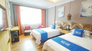 A hotel room with two beds, a desk, a chair, and a window with curtains.