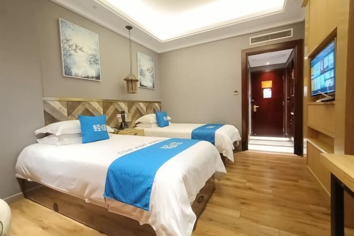 A hotel room with two beds, a TV, and artwork on the walls.