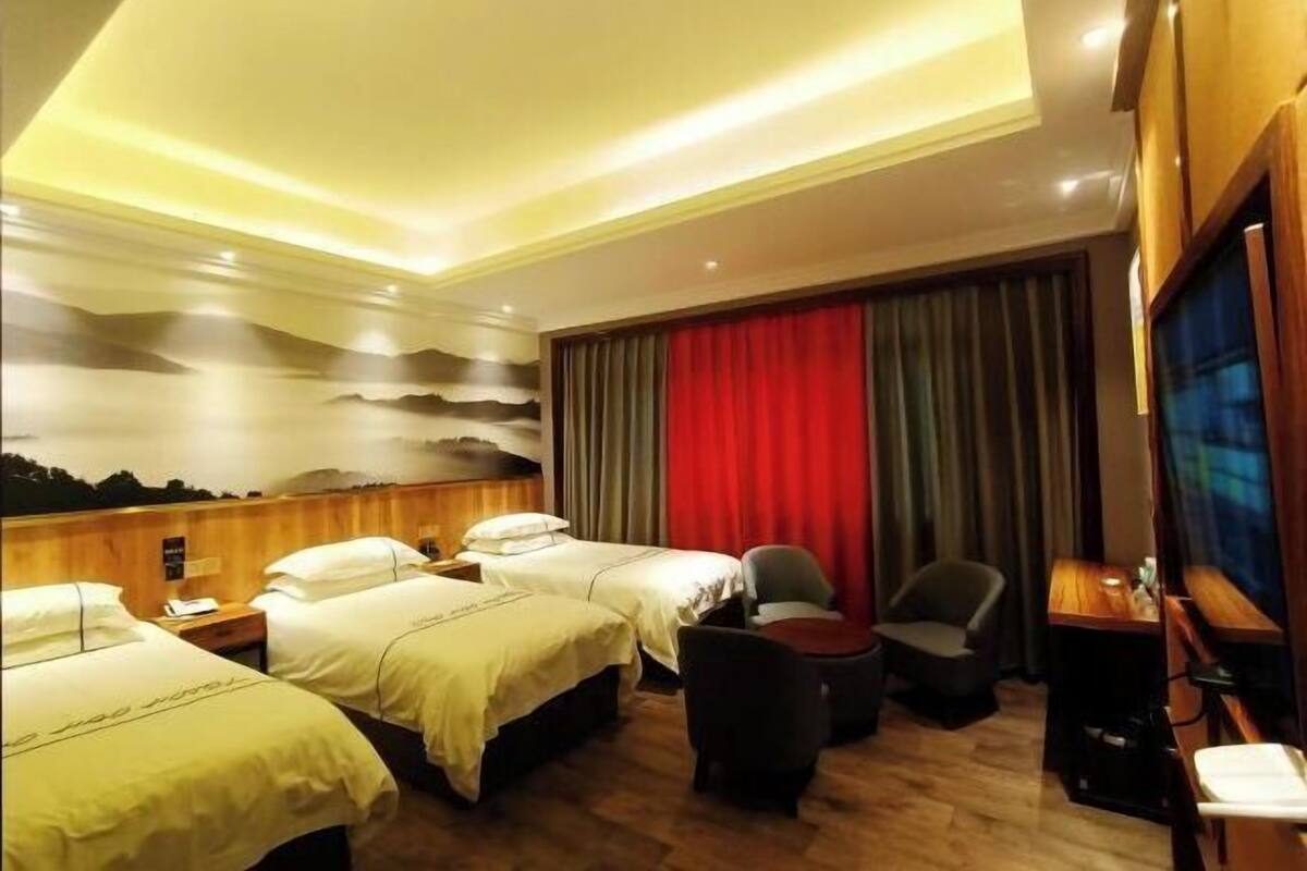 Une chambre d’hôtel avec deux lits, un bureau, une chaise et un téléviseur.