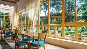 A restaurant with large windows, wooden tables, and blue chairs.