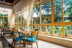 A restaurant with large windows, wooden tables, and blue chairs.