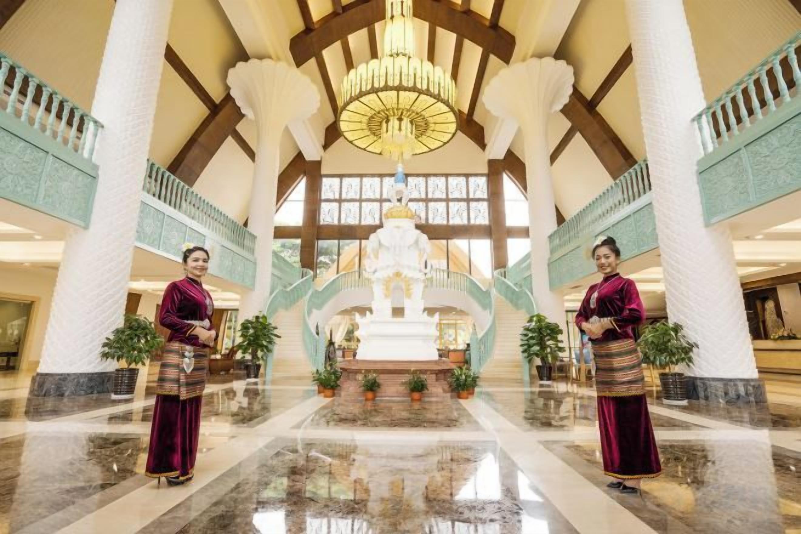 Eine geräumige Lobby mit einer zentralen Statue, hohen Decken und einem Kronleuchter.