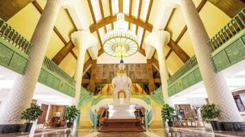 Eine prachtvolle Lobby mit einer zentralen Treppe, großen Säulen und einem Chandelier.