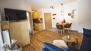 A compact living space with a kitchenette, a dining area, and a seating area with a TV and a basket.