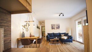 A spacious living area with a wooden dining table, a blue sofa, and a wooden floor.