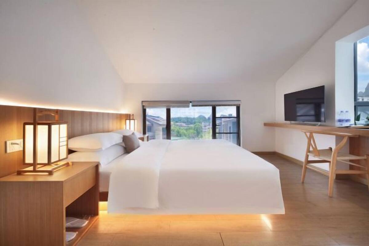 Ein modernes Hotelzimmer mit einem großen Bett, einem Schreibtisch und einem Fernseher.