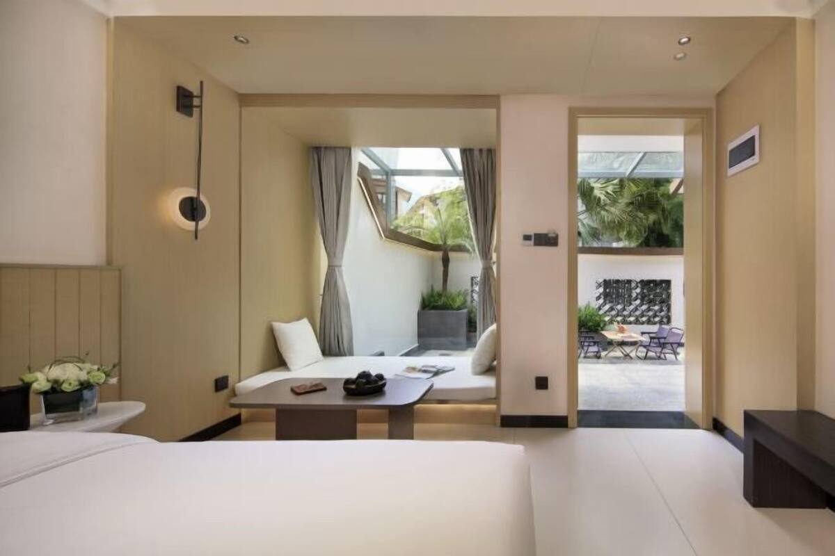 Ein Hotelzimmer mit Bett, kleinem Tisch, einer Sitzecke mit Blick und einem Balkon.