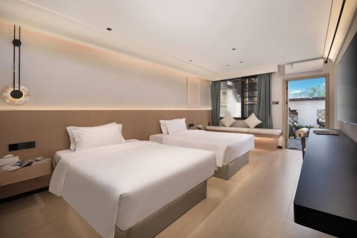 Ein modernes Hotelzimmer mit zwei Betten, einem Schreibtisch und Blick ins Freie.
