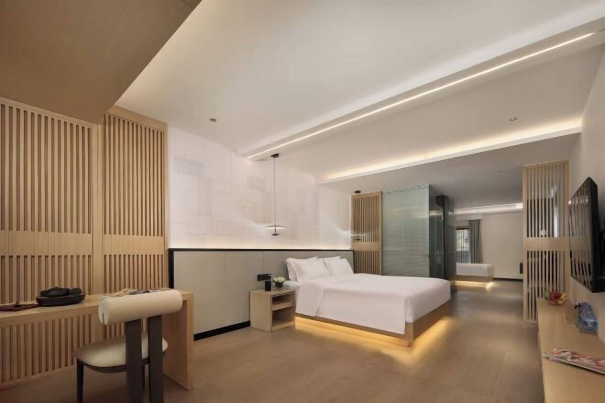 Ein modernes Hotelzimmer mit Bett, Schreibtisch, Stuhl und Fernseher.