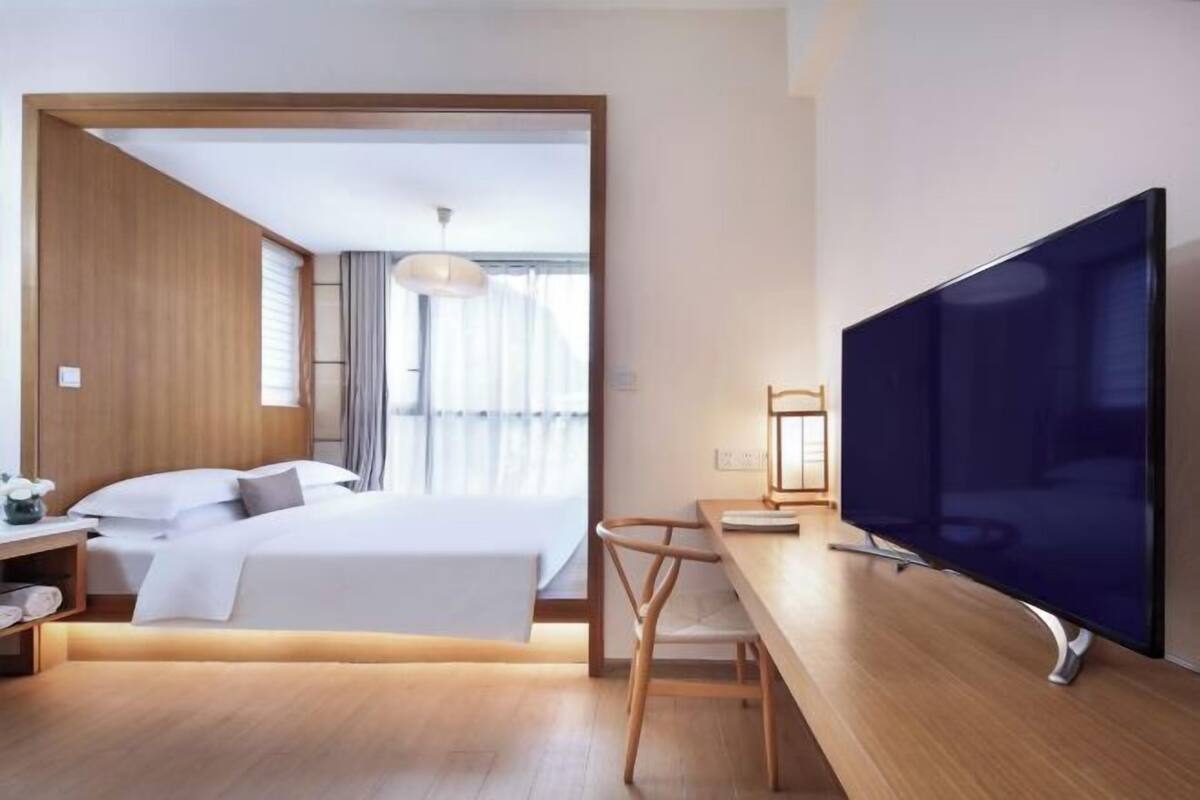 Ein modernes Hotelzimmer mit einem Bett, einem Schreibtisch und einem Flachbildfernseher.