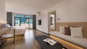 Een moderne hotelkamer met een bed, een bank, een bureau en een televisie.