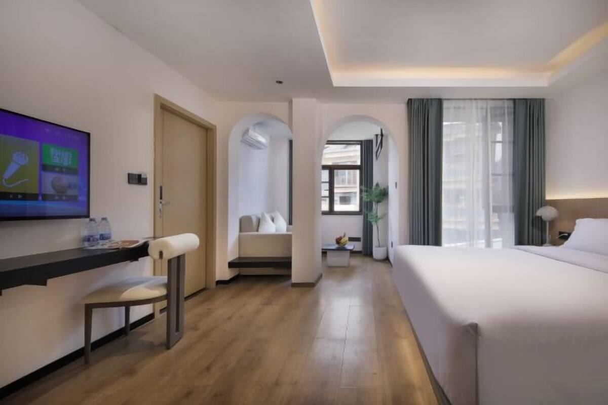 Ein Hotelzimmer mit Bett, Fernseher, Schreibtisch mit Stuhl und einer Sitzecke.