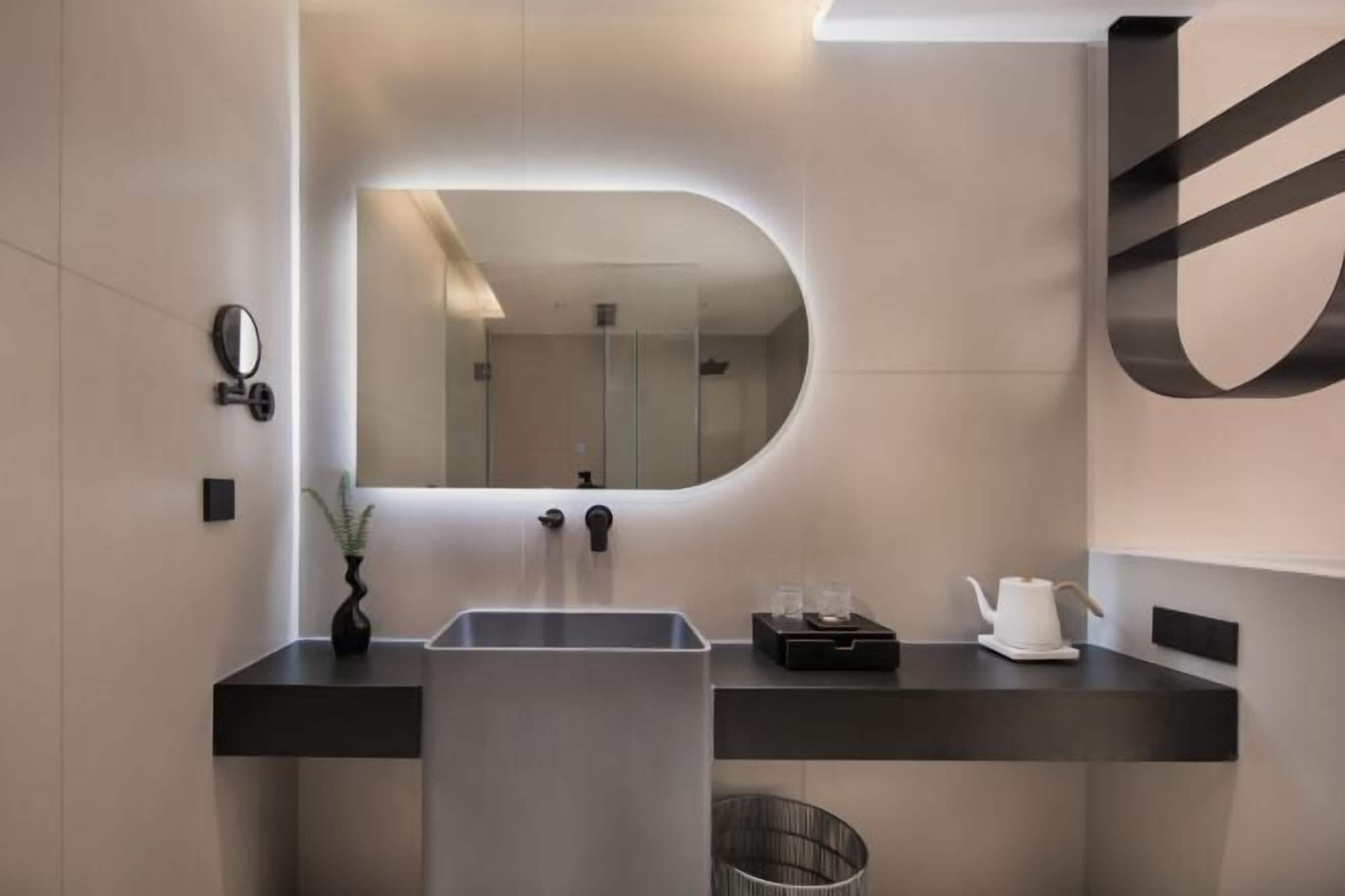 A modern bathroom with a large mirror, a sink, and a towel rack.
