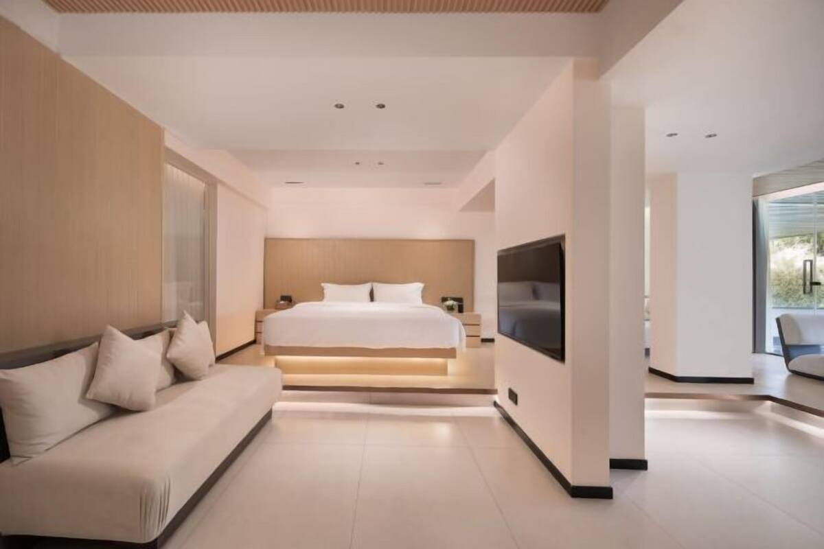 Ein modernes Schlafzimmer mit einem großen Bett, einer Couch und einem Fernseher.