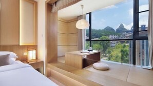 Een moderne hotelkamer met een groot raam, een bed, een bureau en uitzicht op de stad.