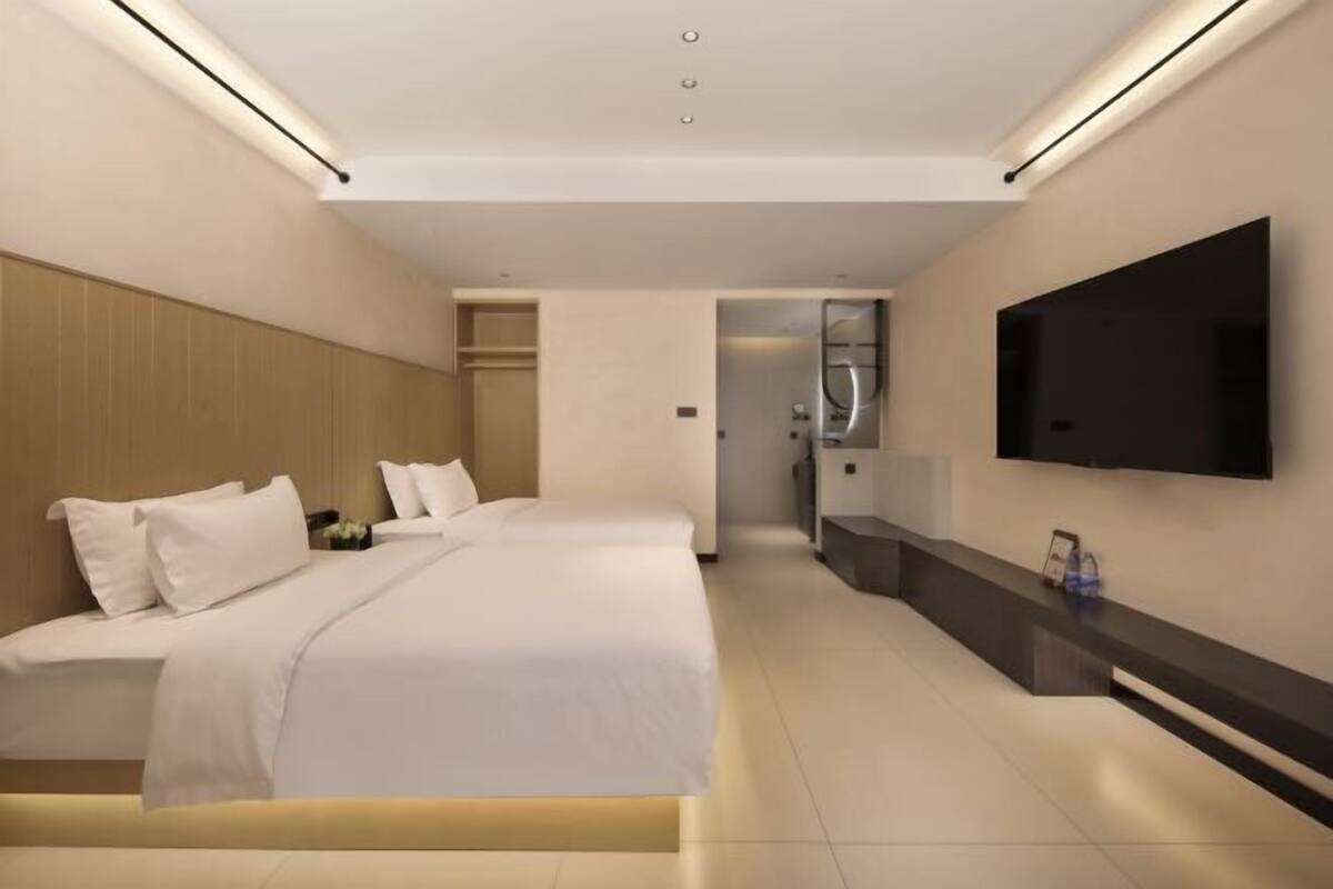 Ein modernes Hotelzimmer mit einem großen Bett, einem flachbildfernseher an der Wand und einem minimalistischen Design.