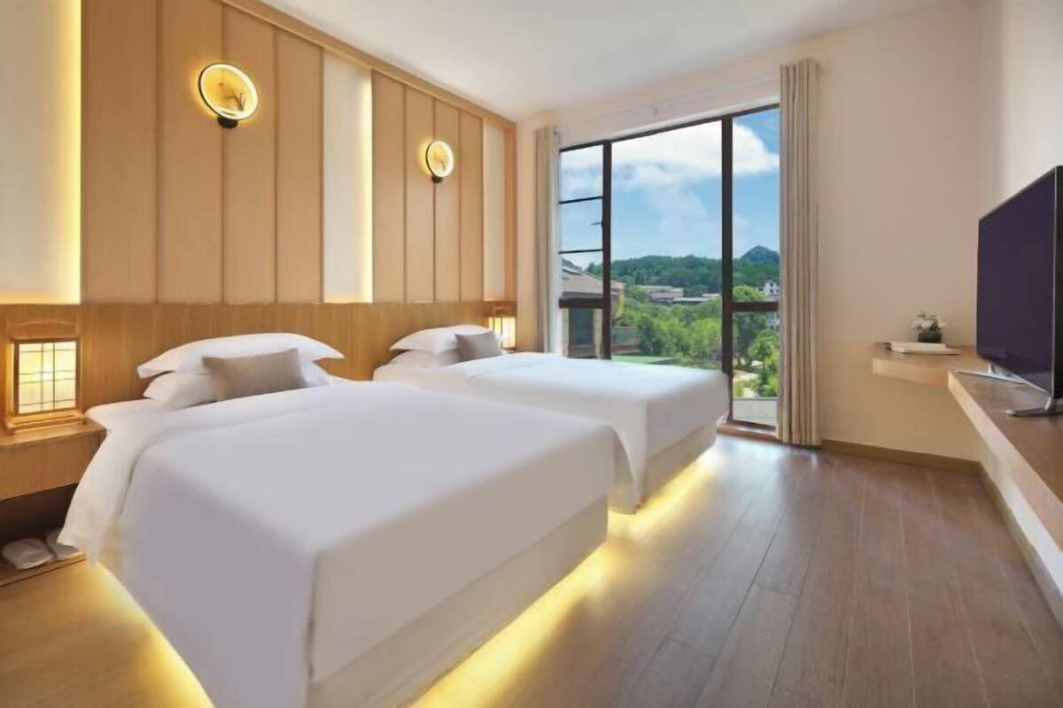 Ein Hotelzimmer mit zwei Betten, einem großen Fenster mit Blick und einem Flachbildfernseher.
