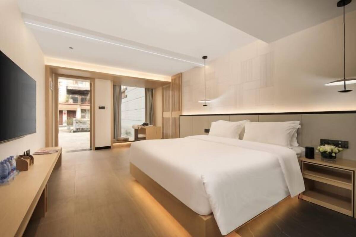 Ein modernes Hotelzimmer mit einem großen Bett, einem Schreibtisch mit Stuhl und einem Fernseher.