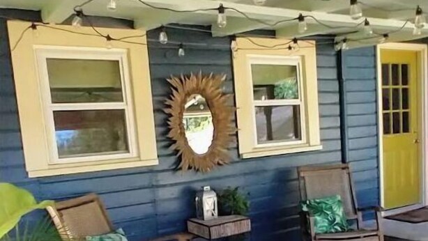 A porch with two rocking chairs, a small table, and a mirror.