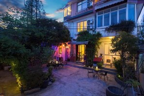 A courtyard with outdoor seating, a building with multiple windows, and a well-maintained garden.