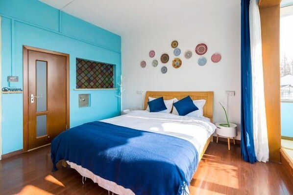 Quarto com cama, porta de madeira, janela com persianas e parede com detalhes circulares.