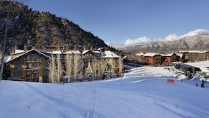 A snow-covered ski resort with multiple buildings, including a lodge with a prominent wooden facade and a ski lift visible in the background.