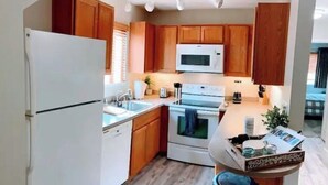 A modern kitchen with wooden cabinets, a white refrigerator, a microwave, an oven, and a sink.