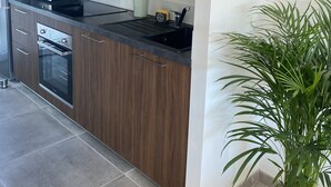 Een moderne keuken met houten kastjes, roestvrijstalen apparatuur en een plant in pot.