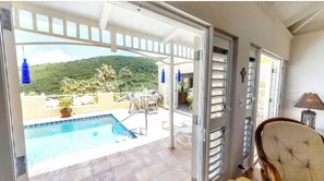 Un balcone con piscina, una sedia e vista su una montagna.