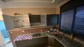 Eine Küche mit einer Granitabdeckung, einem eingebauten Herd und einem Fenster mit Jalousien.
