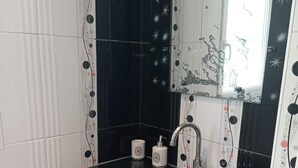 A bathroom with a glass sink, a mirror, and a toilet.