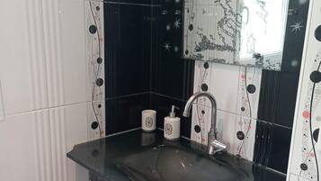 Et badeværelse med vask af glas, et spejl og et toilet.
