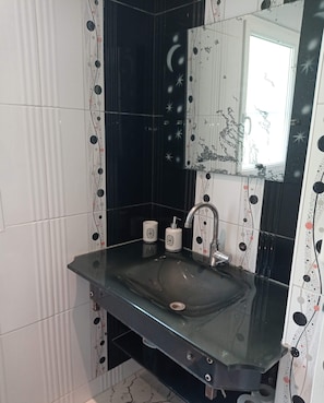 A bathroom with a glass sink, a mirror, and a toilet.
