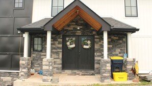 A house with a stone facade, a black front door, and a wooden gable. - High tech modern farmhouse in Franklin, NY (Franklin)