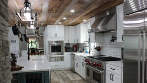 A modern kitchen with white cabinets, stainless steel appliances, and a wooden ceiling. - High tech modern farmhouse in Franklin, NY (Franklin)
