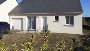 A single-story house with a grey roof, white exterior walls, and a fenced yard.