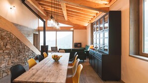 Cozinha moderna com mesa de madeira, cadeiras amarelas e parede de pedra.