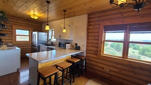 A cabin-style kitchen with wooden walls, a marble countertop, and bar stools.