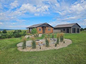 A log cabin with a stone fire pit surrounded by a landscaped garden.